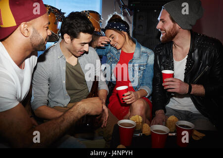 Un gruppo di giovani persone alla moda la refrigerazione in night club, bere birra e divertirsi Foto Stock