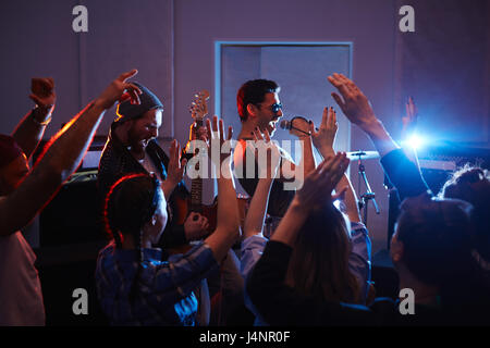 Bello basculante musicisti sul palco di urban club con la folla che acclamava e ballo persone festa dei bracci di sollevamento Foto Stock