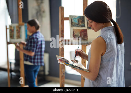 Vista posteriore Ritratto di giovane studentessa in classe d'arte, pittura immagine olio su tela Foto Stock