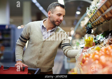 Ritratto di sorridere uomo bello fare la spesa nei supermercati, la scelta di prodotti alimentari dal ripiano Foto Stock