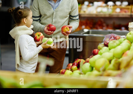 Ritratto di carino bambina con il papà scegliendo fresche mele mature e altri frutti nel supermercato Foto Stock