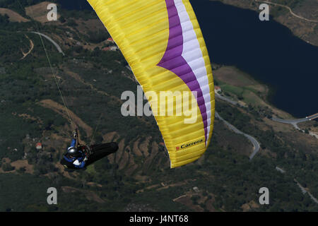 Un parapendio vola sopra la Barragem do Caldeirao, vicino Guarda, Portogallo Foto Stock