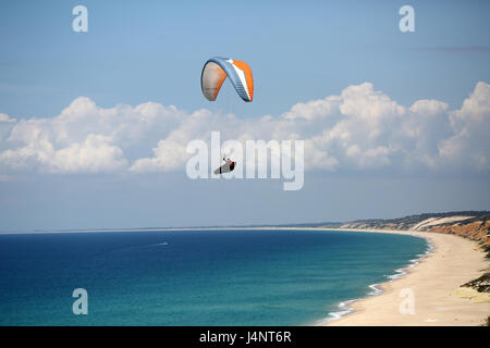 Un pilota di parapendio volare sopra le onde di Aberta Nova Beach. Foto Stock