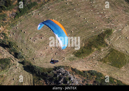 Un parapendio vola sopra haystacks a Linhares da Beira, Portogallo Foto Stock