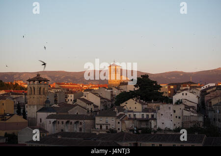 Un livello di visualizzazione sun colpendo la Iglesia del Salvador Segovia ombra townscape skyline al tramonto con gli uccelli rondini in volo il cielo di riempimento Spagna Foto Stock