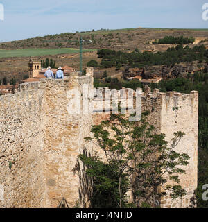 Due uomini turisti persone con cappelli cappello in cima a piedi lungo la parte superiore old antica pietra medievali storiche mura della città dentelli rovine a Segovia, Spagna Foto Stock