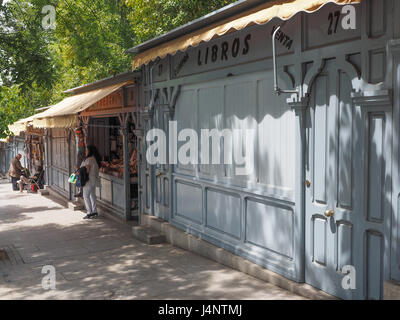 Una vista di shop bancarelle con tende da sole sul marciapiede marciapiede, guardando giù per la collina, alcuni imbarcati up chiusa per la siesta, su Calle de Alfonso XII, Madrid, Spagna Foto Stock