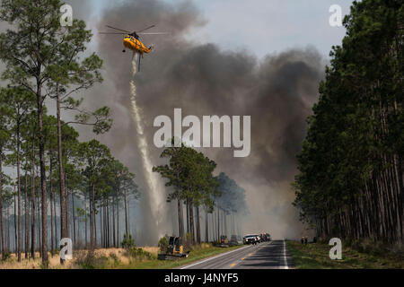 Un elicottero gocce acqua lungo l'autostrada 177 per controllare il West Mims wildfire si diffonde in tutto il Okefenokee National Wildlife Refuge lungo il confine tra la Georgia e la Florida 25 Aprile 2017 nei pressi di San Giorgio, Georgia. Circa 130.000 acri o circa un terzo del rifugio, hanno bruciato che è iniziato il 6 aprile a causa di condizioni di asciutto. Foto Stock