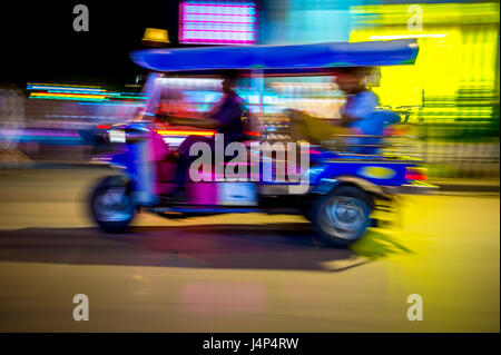 Un classico motorizzato di tuk-tuk taxi esegue lo zoom in una notte di sfocatura di luci al neon a Bangkok, in Thailandia Foto Stock