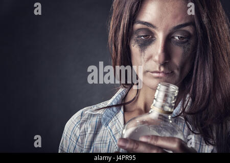 Giovane bella donna in depressione, bere alcool su uno sfondo scuro Foto Stock