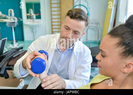 Terapista braccio facendo esercizi con i pesi per migliorare la forza del braccio Foto Stock