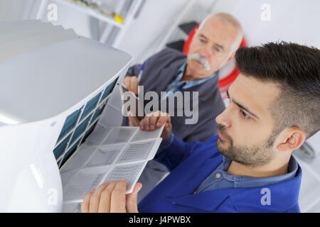 Insegnante osservando gli studenti che lavorano su dispositivi elettrici Foto Stock