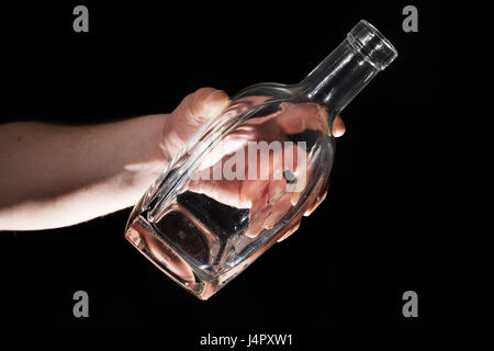 Mano d'uomo tenendo la bottiglia vuota di alcool su sfondo nero Foto Stock