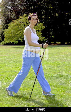 Donna incinta in estate continua a montare con il Nordic Walking, modello rilasciato, Foto Stock