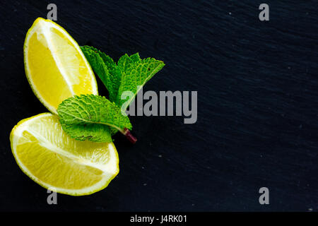 Tagliare e tutto il lime e foglie di menta sulla pietra nera Scheda spazio di copia Foto Stock