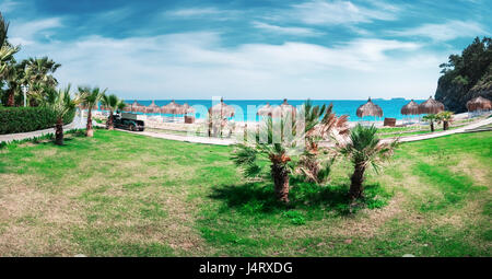 Estate mandrini sulla spiaggia. Vista mozzafiato sul mar Mediterraneo. Legno bianco summerhouses sulla giornata di sole. Cielo blu e nuvole soffici Foto Stock