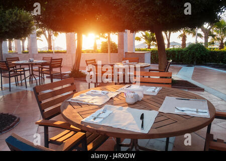 Ristorante estivo sulla spiaggia, vicino al Mar Mediterraneo. Mobili in legno e tovagliolo bianco Foto Stock