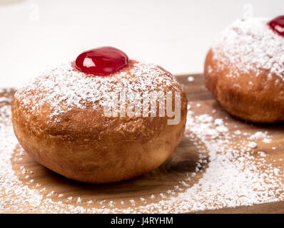 Sufganiyah (sufganiyot) una tradizionale ciambella ebraica mangiato durante Hanukkah confettura rossa e zucchero in polvere. Su sfondo bianco Foto Stock