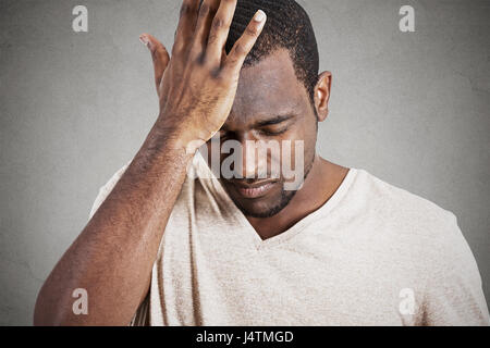 Closeup headshot molto triste depresso, ha sottolineato, da soli, deluso cupo giovane testa su mani avente pensieri suicidi isolato muro grigio backgrou Foto Stock