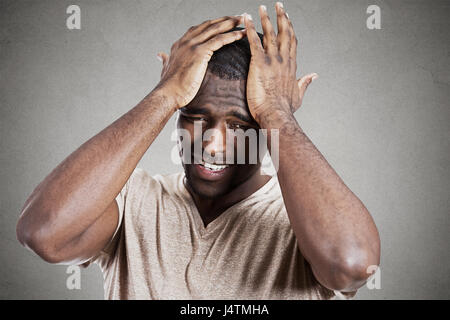 Closeup headshot molto triste depresso, ha sottolineato, da soli, deluso cupo giovane testa su mani avente pensieri suicidi isolato muro grigio backgrou Foto Stock