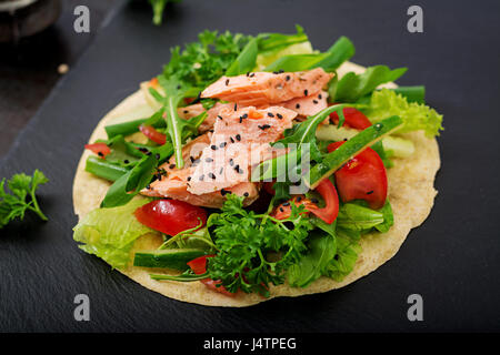 Una sana mais messicano tacos con salmone al forno, lattuga, pomodoro, cetriolo e foglie di rucola. Foto Stock