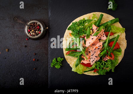 Una sana mais messicano tacos con salmone al forno, lattuga, pomodoro, cetriolo e foglie di rucola. Lay piatto. Vista dall'alto. Foto Stock