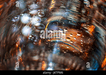 Un'immagine ad esplorare la combinazione di acqua e le goccioline di olio e come essi interagiscono con la luce colorata. Foto Stock