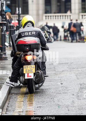 Uber mangia il cibo del corriere per la consegna si prepara a lasciare un ristorante per offrire a un cliente il pasto. Foto Stock