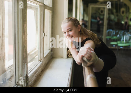 Giovane bella Ballerina Ballerina in fase di riscaldamento nella classe di balletto. Ragazza stiro a lezioni di ballo Foto Stock