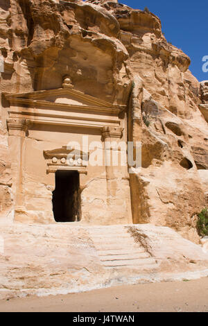 Antica facciata scolpita con le colonne e le travi in rilievo che circonda un ingresso in una grotta sepolcrale in poco Petra, antica città Nabataen in Giordania. Foto Stock