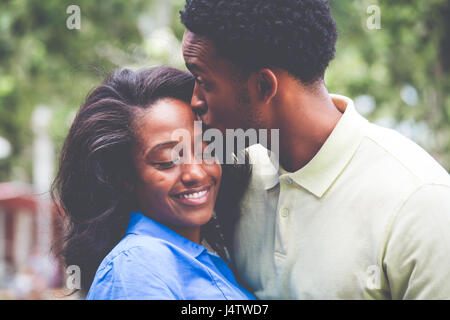 Closeup ritratto di una giovane coppia, ragazzo in maglietta gialla kissing donna con la maglietta blu, momenti felici, positivo le emozioni umane su isolati fuori all'aperto Foto Stock
