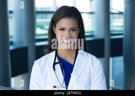 Closeup headshot ritratto di cordiale e sorridente fiducioso femmina, professionisti sanitari con camice, isolata all'interno di office background. Vi paziente Foto Stock