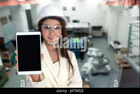 Asia giovane ingegnere femmina utilizzando lo schermo nero tablet , indossare gli occhiali e cappello bianco in smart factory. 4 settore internet delle cose concetto. Foto Stock