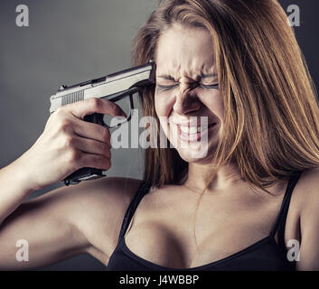 Donna con pistola puntando sul suo capo Foto Stock