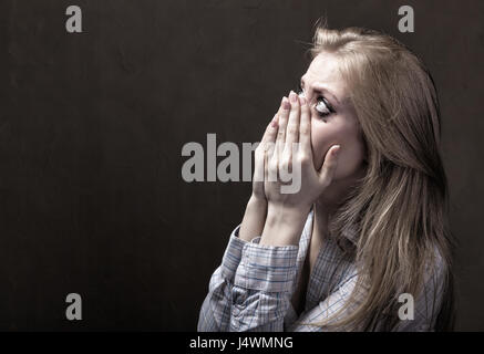 Giovane donna piange disperatamente su sfondo scuro Foto Stock