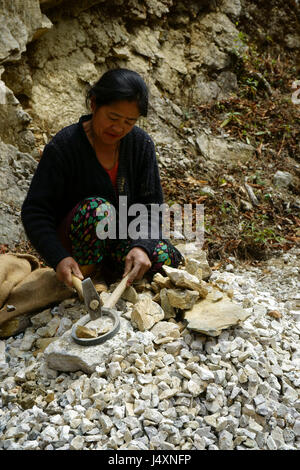 Donna crshing rock con un martello per la costruzione di strade, Rinchenpong, Sikkim, Indiia Foto Stock