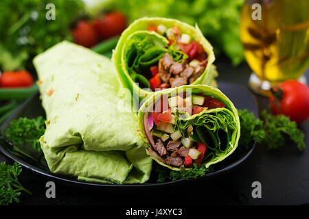 Shawarma da succosa carne di manzo, lattuga, pomodori, cetrioli, la paprika e la cipolla nel pane pita con spinaci. Menù dietetici Foto Stock