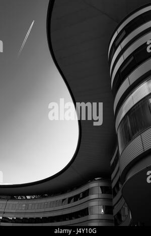 Un tetto curvo di un edificio la traccia di un s, con sky sul background e un irplane contrail Foto Stock