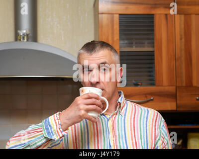Uomo di bere un tè o un caffè in una cucina, il fuoco selettivo indoor shot Foto Stock