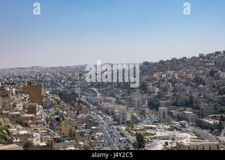 Vista di Amman moderna e i vecchi edifici tra cui il Teatro Romano sotto la collina della cittadella di Amman. Opaco blu del cielo è sopra. Foto Stock