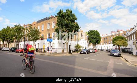 Londra, Inghilterra - Luglio 14, 2016: Un ciclista passa a schiera case di città in un prospero quartiere residenziale di Islington nel nord di Londra. Foto Stock