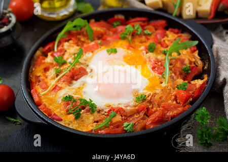 La prima colazione. Uova fritte con verdure - shakshuka in una padella su uno sfondo nero in stile turco. Foto Stock