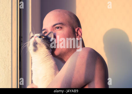 Malinconici uomo tenendo un gatto al tramonto Foto Stock