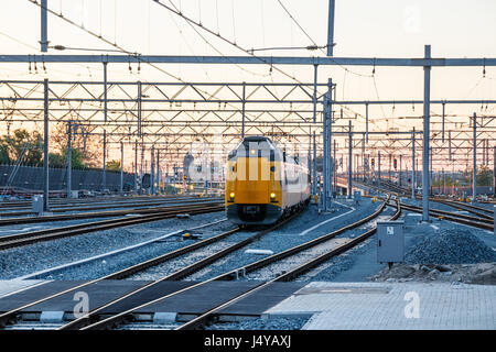 Nord cantiere ferroviario di Utrecht Centraal stazione ferroviaria con l'avvicinamento di un treno passeggeri durante il tramonto. Utrecht, Paesi Bassi. Foto Stock