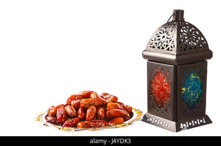 Splendido splendente Fanus lanterna e datteri secchi su un vassoio d'argento isolamento su sfondo bianco. La festa islamica del mese sacro del Ramadan Kareem Foto Stock
