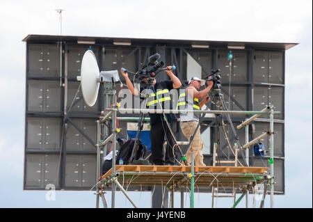 Multimediali evento troupe riprese riprese video su schermo gigante dietro di loro all'Airshow di Farnborough, Regno Unito sulla luglio 24, 2010 Foto Stock