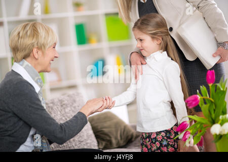 Bambina introduzione la sua nuova babysitter, ragazza timidamente agitare le mani con donna matura Foto Stock