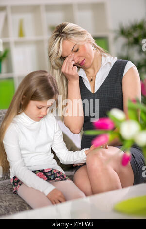 Ragazza triste seduto sul divano accanto preoccupato mamma a casa Foto Stock