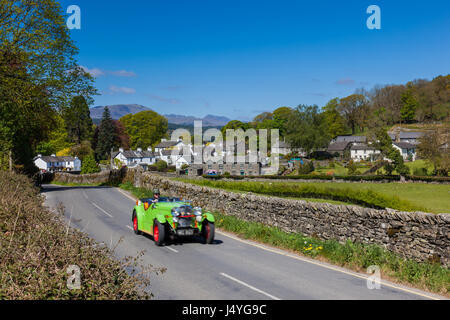 Classic car lo zoom attraverso il villaggio di Near Sawrey, vicino a Ambleside, Lake District, Cumbria Foto Stock