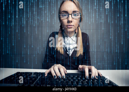 Nerd ragazza utilizzando un computer con codice binario sullo schermo Foto Stock